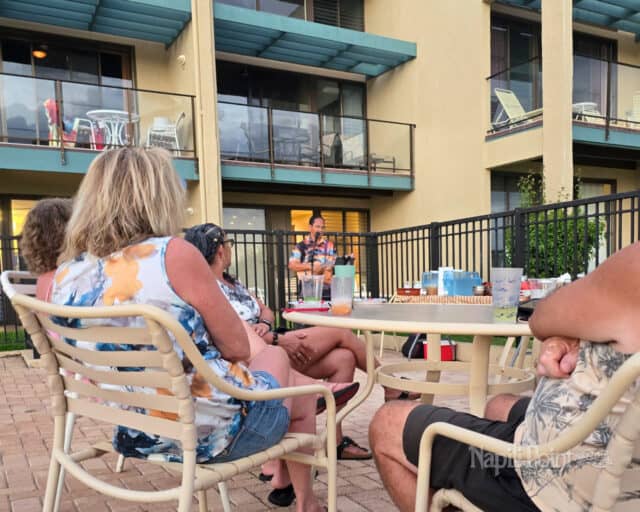 Man playing ukulele with people in pool chairs watching